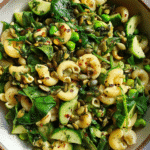 Vegan pasta salad in rustic bowl with green veggies and herbs