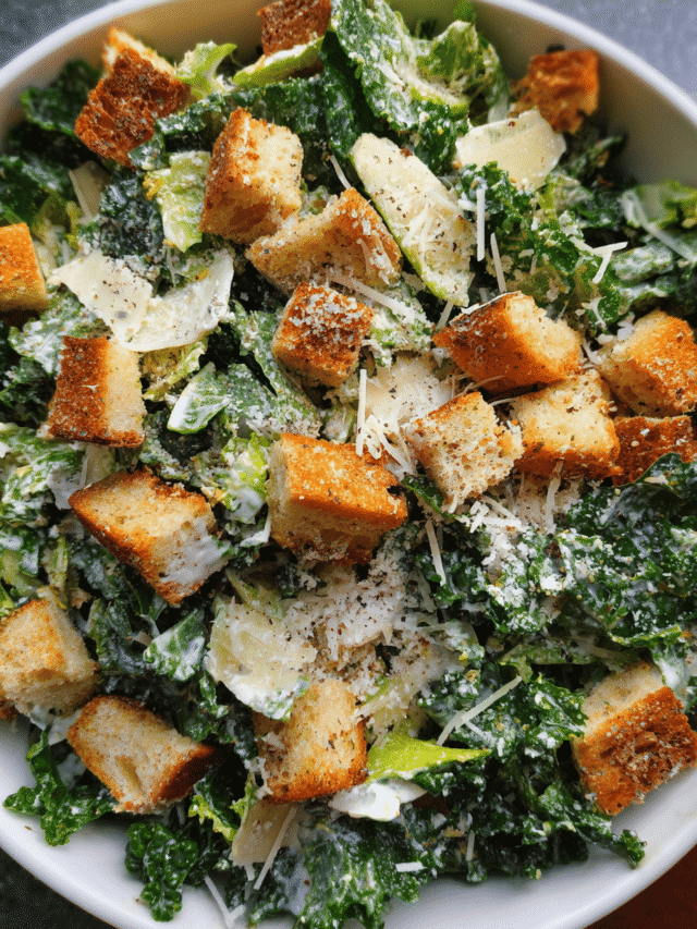 kale caesar salad in bowl with creamy dressing and croutons