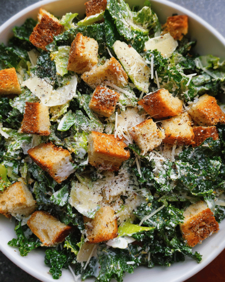 kale caesar salad in bowl with creamy dressing and croutons