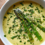 Creamy asparagus soup in bowl with garnish