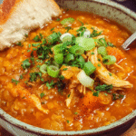 Bowl of red lentil chicken soup with garnish