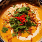 Bowl of Thai Coconut Pumpkin Soup with garnishes and flatbread