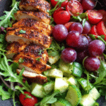 Blackened chicken and grape arugula salad in a rustic bowl