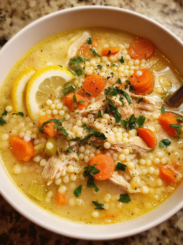 Creamy chicken couscous soup in a bowl with vegetables and parsley