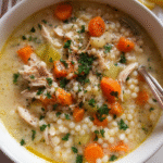 Creamy Chicken Couscous Soup in a bowl with vegetables and herbs