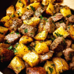Garlic butter steak bites with potatoes in a cast iron skillet
