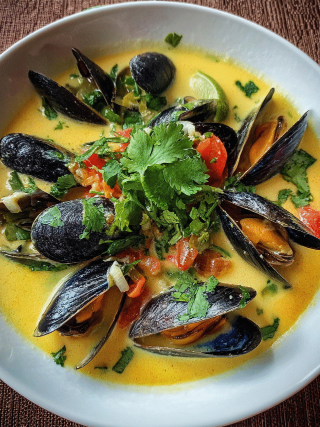 bowl of coconut mussel soup with herbs