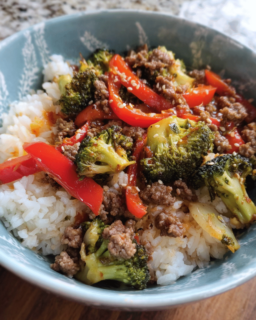 Beef and vegetable rice bowl with ground beef, broccoli, and bell peppers over brown rice