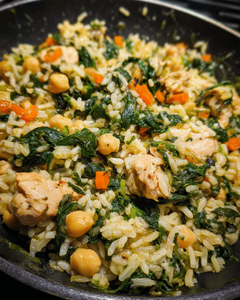 Chicken and spinach rice served in a skillet with fresh greens