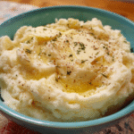 Creamy mashed potatoes topped with melted butter in a baking dish