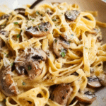Creamy mushroom pasta in a skillet garnished with Parmesan