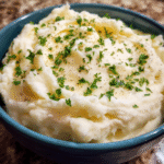 Creamy mashed potatoes in a bowl with butter and herbs
