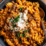 One pot creamy tomato beef pasta in a white bowl with parmesan and parsley