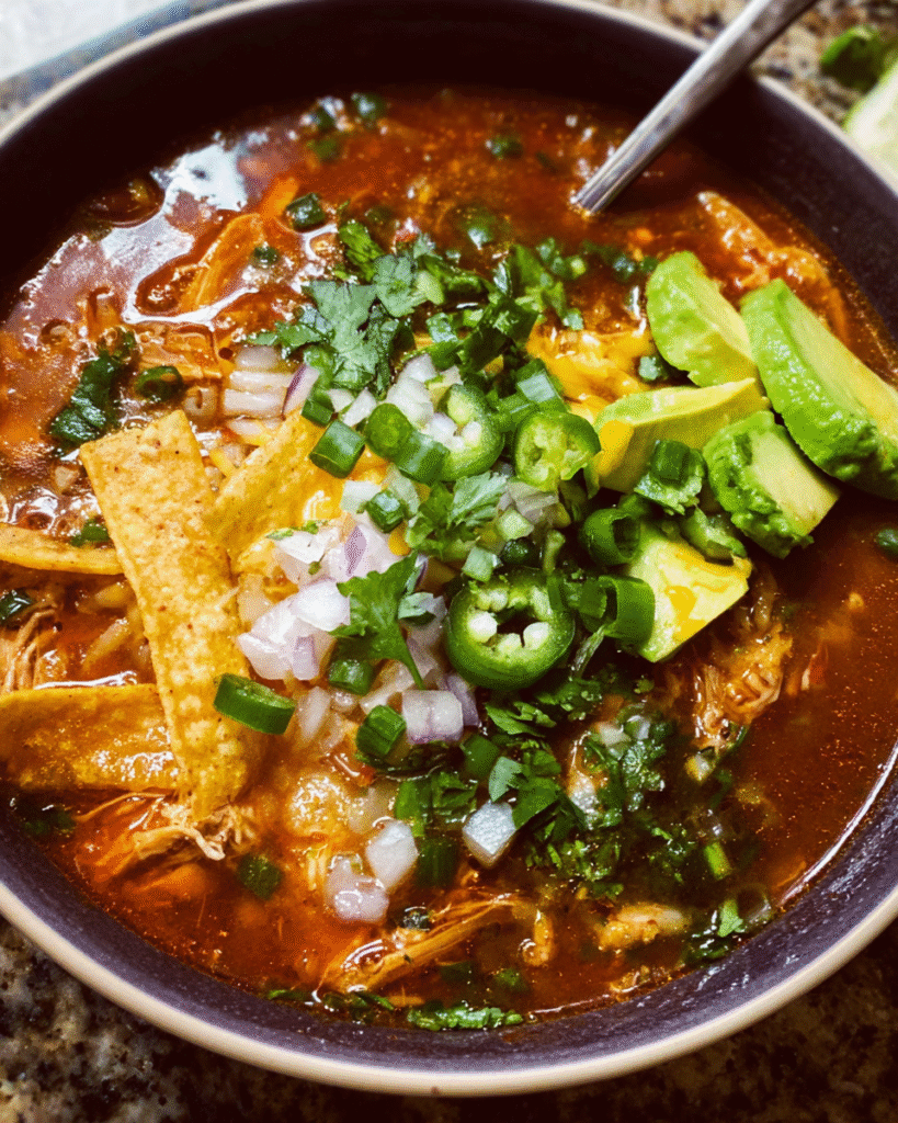 Spicy tortilla soup with chicken and toppings in a bowl