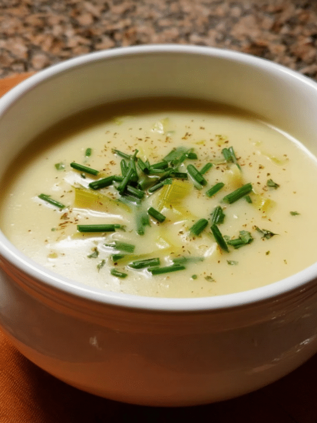 Creamy homemade potato leek soup in white bowl with chives on top