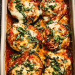 Cheesy layered marinara baked eggplant slices with melted cheese and basil