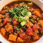 Bowl of chipotle turkey sweet potato chili topped with avocado and cilantro
