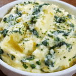 Creamy spinach potatoes served in a bowl with melted cheese and wilted spinach