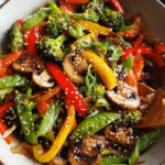 Easy veggie stir fry with broccoli, peppers, and sesame seeds in a skillet